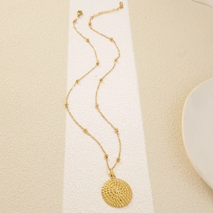 Elegant gold geometric necklace featuring a textured circular pendant and beaded chain