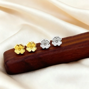 Matte finish clover stud earrings in gold and silver set on champagne silk fabric