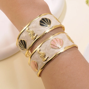 Dettaglio del set di bracciali a polsino nautici dorati con motivi di cavalluccio marino