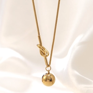 Golden knot snake chain necklace with polished round ball pendant on silk background