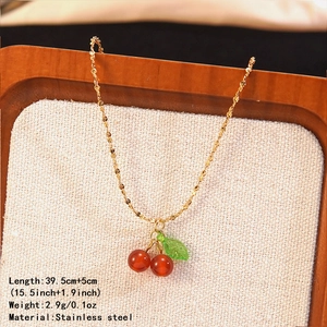 Detailed view of red cherry pendant on a gold stainless steel chain with size info
