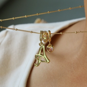 Nahaufnahme der goldenen Halskette mit Buchstabe A und rosa Zirkonia-Herzanhänger
