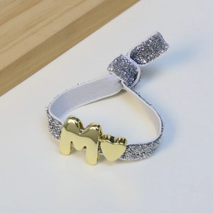 Pulsera elástica con banda plateada brillante y colgantes dorados de corazón y letra M