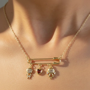 Collana a spilla dorata con gemma a cuore e ciondoli bimbi indossata sul collo