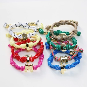 Colorful braided rope bracelets with polished gold alphabet charms and adjustable knots
