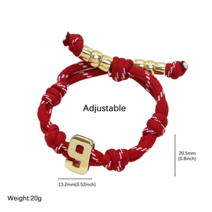 Detail view of red woven rope bracelet with gold number 9 pendant and adjustable drawstring