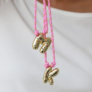 Adjustable woven necklace featuring gold M and K bubble pendants with multi-color gemstones