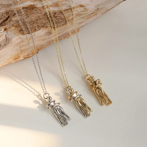 Detailaufnahme von Umarmungs-Anhängern in Silber, Gold und Bi-Color mit poliertem Finish