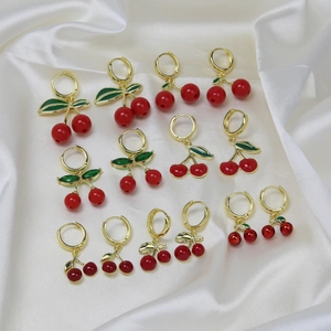 Detail showing various sizes of gold cherry earrings with red fruit and green enamel leaves