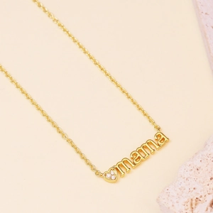 Collar dorado con colgante mama y corazón con circonitas sobre fondo beige suave