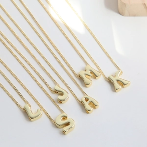 Macro view of 18k gold plated 3D alphabet pendants on delicate metal chains