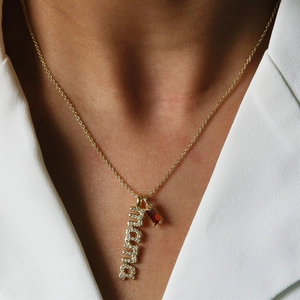 Gold mama necklace with sparkling cubic zirconia and red birthstone on a model
