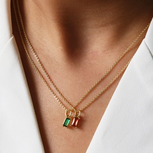 Gros plan de colliers dorés superposés avec pendentifs rectangulaires en pierres colorées