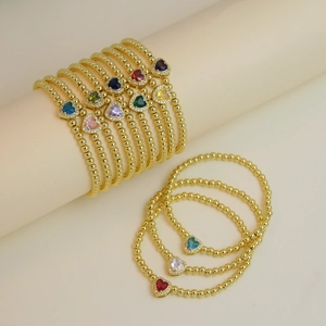 Close-up of 18k gold beaded bracelets with colorful heart-shaped crystal charms