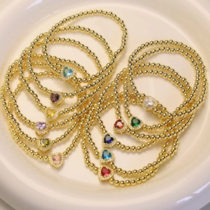 Golden bead bracelets with 12 colorful heart-shaped birthstones displayed on a ceramic plate