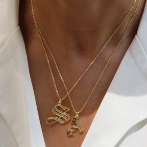 18k gold plated alphabet necklace with micro-paved zircons worn by model over white suit