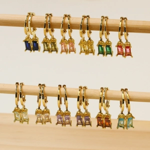 Golden hoop earrings with colorful rectangular birthstones displayed on wood