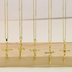 Detail view of five gold-plated brass cross necklaces with intricate floral motifs and stones