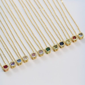 Collezione di dodici collane con pietre portafortuna quadrate su sottili catene d'oro