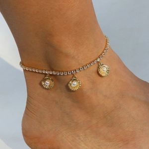Detail of gold shell anklet with sparkling zircon crystals and white pearls for summer beach