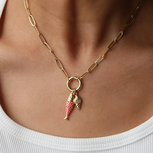 Gold paperclip necklace with red fish and spiral shell pendants worn on model