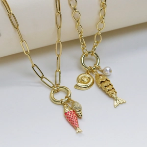Macro shot of gold marine necklaces featuring shell, red enamel fish, and pearl charms