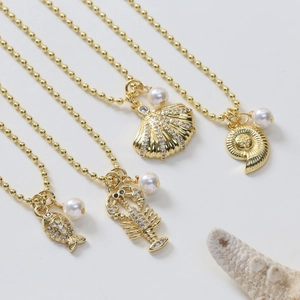 Detail of gold ocean pendants featuring lobster, fish, shell, and starfish with pearls