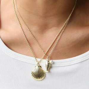 Double-layered gold necklace with starfish fish and pearl pendants on white fabric