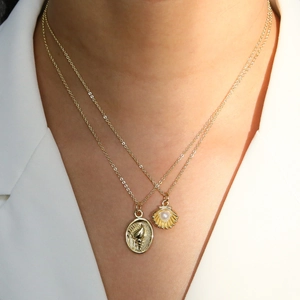 Double-layered gold necklace with a seashell pearl pendant and oval vintage relief coin