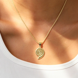 Gros plan du collier à pendentif nautile doré sur chaîne corde porté par un modèle