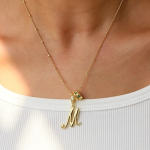 Collana placcata oro 18k con lettera M corsiva e ciondolo con gemme verdi e bianche