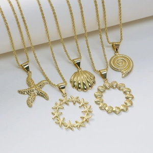 Colliers dorés thème océan avec pendentifs étoile de mer et coquillages sur support blanc