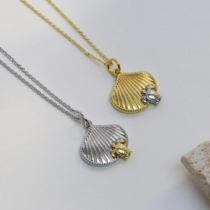 Detail van schelp- en schildpadkettingen in goud en zilver op natuursteen decoratie