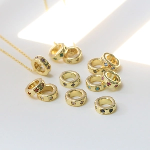 Gold birthstone wheel charm necklaces with colorful cubic zirconia gems on white surface