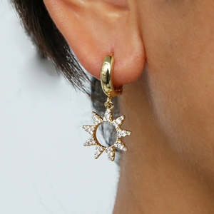 Gros plan sur les boucles d'oreilles soleil en laiton doré serties de zircons brillants