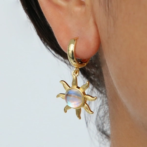 Gros plan de boucles d'oreilles soleil rétro en laiton avec incrustation d'opale
