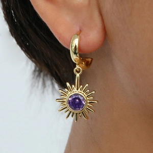 Gros plan d'une boucle d'oreille tournesol dorée avec zircon violet portée par mannequin
