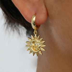 Détail d'une boucle d'oreille soleil vintage en laiton avec yeux en zircon