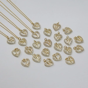 Detailansicht von goldenen Herzanhängern mit Schreibschriftbuchstaben und Kristallen