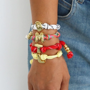 Colorful braided rope bracelets with gold initial pendants worn on a female wrist