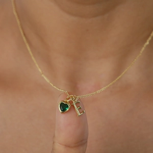 Collana dorata con ciondolo a cuore in pietra verde e un ciondolo con lettera iniziale E