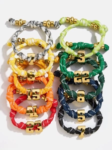 Close-up of colorful braided paracord bracelets with golden lucky number charms in two rows