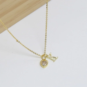 Dettaglio del ciondolo a cuore dorato con zircone e lettera K su catena sottile