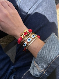 Detailed shot of layered bracelets featuring a red rope with number 23 and evil eye charm