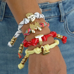 Colorful woven cord lucky number bracelets with gold charms worn over denim