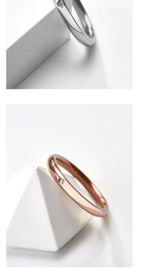 Détail de bagues en acier argent et or rose avec zircon sur supports géométriques blancs
