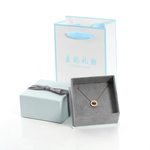 Détail d'un collier en or rose avec chiffres romains et coffret cadeau bleu clair élégant