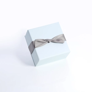 Boîte cadeau bijoux carrée bleu clair avec nœud en satin gris sur fond blanc pur