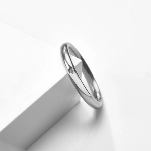 Bague minimaliste en acier titane argenté avec solitaire diamant sur fond blanc