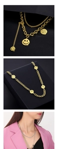Détails des pendentifs smiley dorés et plaque gravée sur une grosse chaîne à maillons